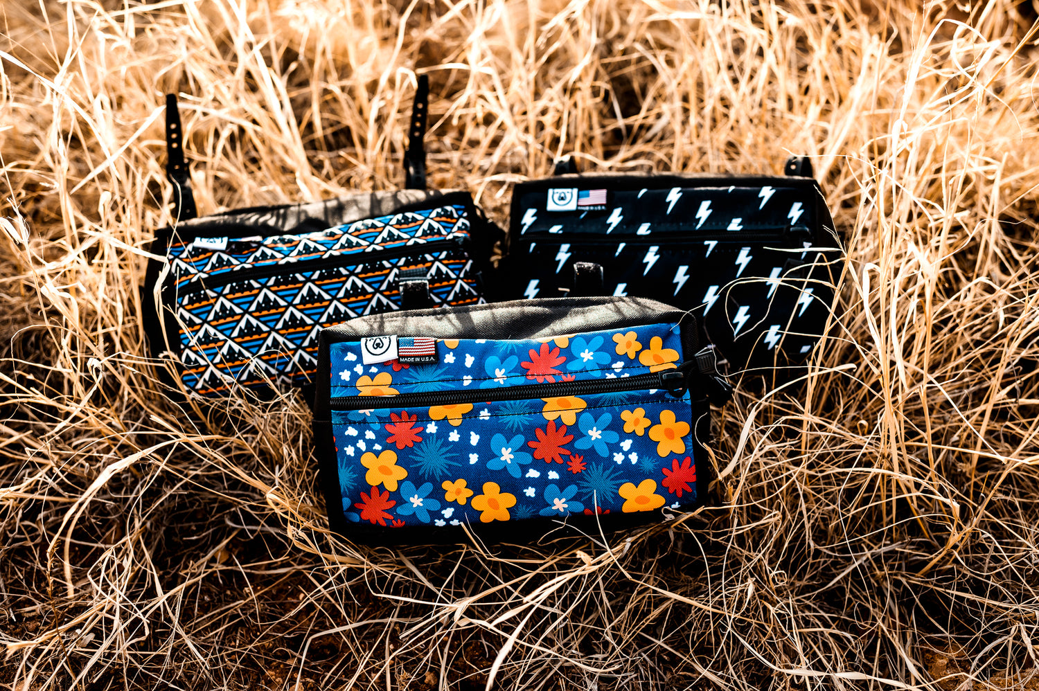 Large handlebar bags for bicycles in orange and blue mountains, black and white lightning bolts, and blue, orange, and red flowers